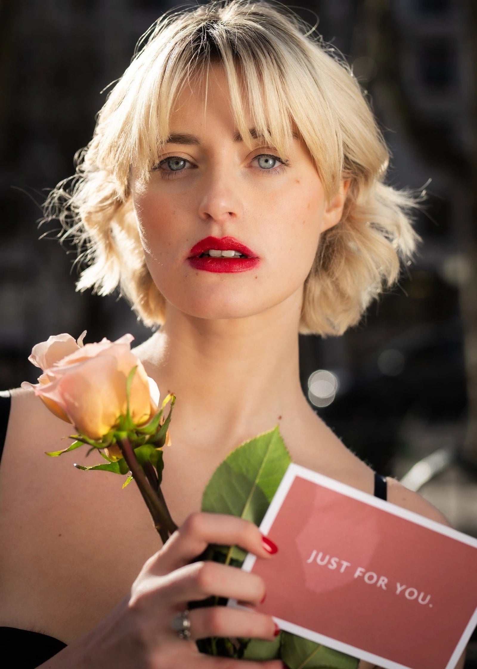 modelo com duas rosas cor de péssego na mão e um cartão Just For You